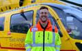 Critical Care Paramedic Liam Sagi standing in front of East Anglian Air Ambulance Helicopter